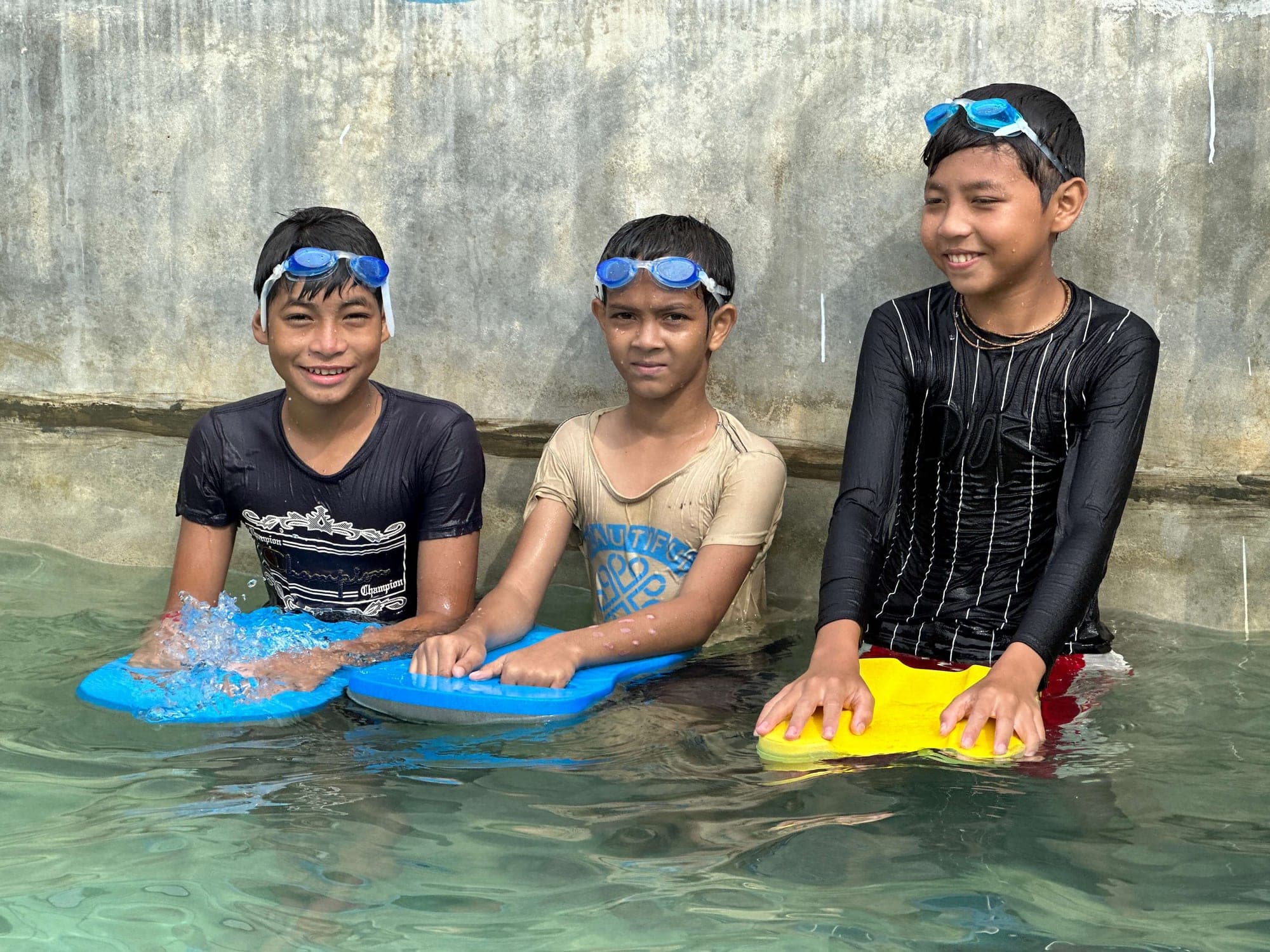 Three students with kickboards in the CAFFE pool